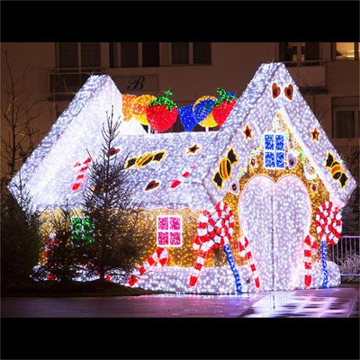 A large, pre-lit LED gingerbread house with colorful decorations and lights displayed outdoors.