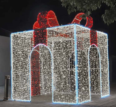 A large, walk-through gift box decoration made of metal frames with white and red LED lights, intended for holiday decorations.